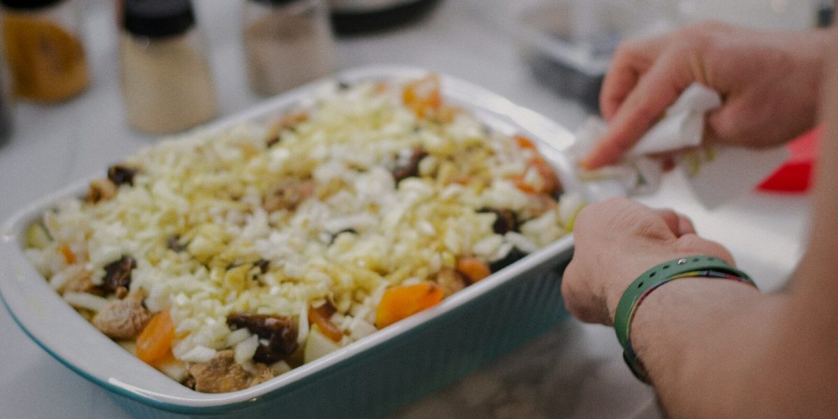 a person putting a piece of food in a casserole dish